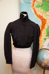 Edwardian black button bodice featuring a high stand collar, white lining, and textured fabric.