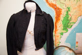 Edwardian era black button bodice displaying textured fabric and puff sleeve detail.