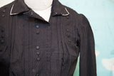 Textured black fabric and white piping on the collar of an Edwardian button bodice.