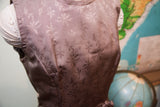 Muted purple-brown vintage dress bodice featuring a subtle, repeating leaf pattern.