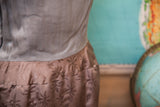 Vintage 60s Asian-inspired dress showing smooth taupe top and patterned brown leaf-motif skirt.
