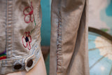 Vintage light-wash denim jacket with red embroidered flowers and unique hand-stitched seam.