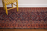 Distinct tribal Belouch rug patterns in saturated madder red, deep indigo, and walnut tones.