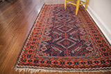 Well-defined madder red and deep indigo blue tribal patterns on a Belouch rug corner.