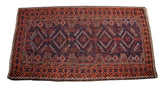 Bottom corner of Tribal Belouch rug, showing defined madder red and indigo blue geometric patterns.