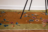 Mustard gold Art Deco rug with vibrant floral tendrils and blue bird motif.