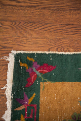 Art Deco Chinese rug corner with green border, red butterfly motif, worn fringe.