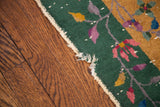 Tattered selvage edge, forest green border, and colorful floral tendrils on the vintage Chinese rug.