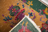 Folded corner of vintage Chinese Art Deco rug, showing green foundation and worn fringe.