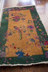 Art Deco Chinese rug: blue floral motif, forest green border, visible knots, worn edge.