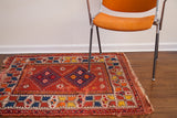 Vintage Turkish rug border with alternating indigo, yellow, and tangerine orange motifs and fringe.