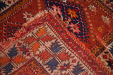 Vintage Turkish rug corner with worn geometric patterns, tattered fringe, and visible foundation.