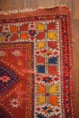Vintage Turkish rug corner detail: geometric borders in tangerine, saffron, indigo with wear.