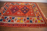 Corner of a vintage Turkish rug showing bright tangerine, saffron, indigo geometric border and edge wear.