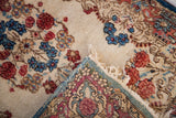 Supple 1940s Kerman floral rug folded to reveal cream pile and detailed woven reverse.