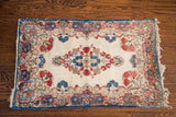 Intricate red, rose, and indigo floral motifs detailing a vintage Kerman rug.