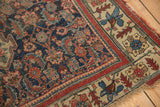 Corner of antique Bijar rug, highlighting indigo, aubergine, saffron floral motifs, and worn fringe.