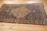 Corner of an antique Bijar rug, with indigo, saffron, red floral border and visible wear.