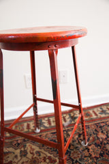 Red chippy paint and adjustable metal legs on the vintage industrial stool.