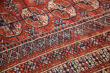 Detailed terracotta, navy, and beige geometric gul patterns on a vintage Bokhara rug.