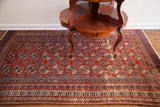 Vintage Bokhara rug detail: red and indigo geometric guls with visible wear.