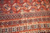 Vintage Bokhara rug with geometric 'gul' motifs, red-navy borders, and areas of exposed foundation.