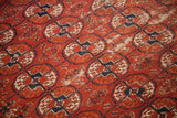 Antique Tekke rug detail showing geometric red, navy, and cream Bokhara gul pattern with visible foundation wear.