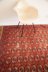 Antique Tekke rug's geometric Bokhara guls in red, navy, and ivory with visible wear.