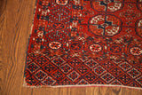 Antique Tekke rug corner detail with rust and deep blue geometric Bokhara patterns, featuring a tattered edge.