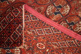 Geometric Bokhara pattern in red, dark blue, and tan, showing woven reverse and tattered edge.