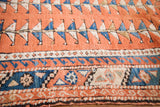 Vintage Turkish rug geometric blue and white triangles on salmon field with patterned border.