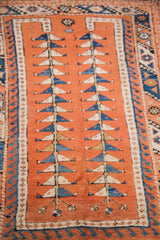 Orange field of a Vintage Melas rug with blue and cream double tree design.