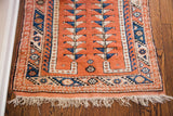 Vintage Melas rug end with peach field, blue geometric borders, tree motif, and white fringe.