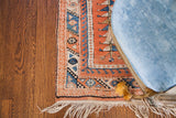 Close-up of hand-knotted fringe and colorful geometric border on a vintage Melas rug.