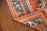 Hand-knotted backing and geometric orange, blue, cream patterns of vintage Turkish rug.
