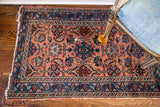 Vintage Hamadan rug's rose field, showing intricate palmettes, serrated leaves, and indigo border.