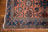 Vintage Hamadan rug corner detail: light rose field, indigo border, snail shell vines.