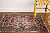 Vintage Lilihan rug's cloudband motif and blossoming flowers on its light rose field.