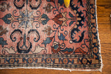 Corner detail of Lilihan rug, rose field, navy floral border, and distressed fringe.