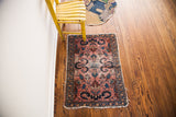 Vintage Persian Lilihan mat with rose field, cloudband motif, and tattered ends.