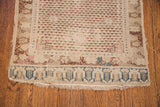 Antique Turkish rug's worn end, featuring blue border motifs and ivory field with faux fringe.