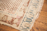 Aged ivory field with soft repeating motifs, blue patterned border, and worn faux fringe of an antique Turkish rug.