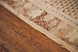 Antique Turkish rug's aged edge, featuring geometric burgundy and teal patterns.