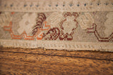 Textured pile and worn edge of an antique Turkish rug with ivory, red, and blue motifs.