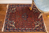 Vintage Bijar rug detail: dense red field, blue border, ivory corner with asymmetric lantern motif.