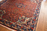 Vintage Bijar rug showing cherry red field, blue medallion, asymmetric lantern, and navy border.