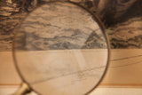 A magnifying glass reveals the 1895 publication date on the antique W. Dendy Sadler etching.