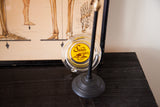 Clear glass Vintage Sands Hotel ashtray with bright yellow logo, partly obscured by a dark stand.