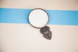 Vintage Handheld Beveled Glass Mirror with ornate dark metal handle.