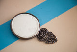 Intricate metal scrollwork and beveled glass edge on vintage handheld mirror.